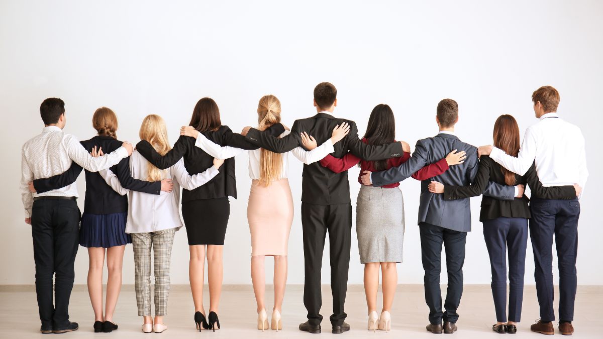 A photo of a group of employees turning their backs with their hands on each other’s back.