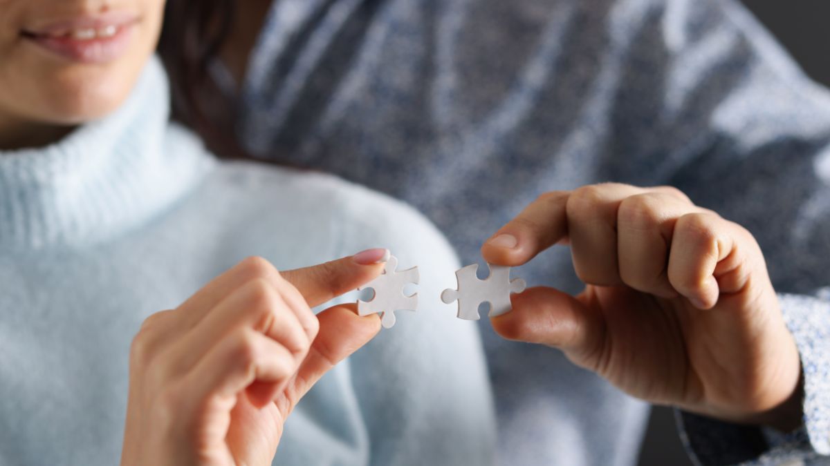 A man and a woman holding puzzle pieces that fit together